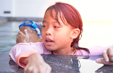 Boy hide and girl and play water near poolside in swimming with sun light,selective focus