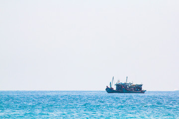 A fishing boat floats on Ko Lipe, Thailand on a day with clear blue sea and beautiful sunny skies.