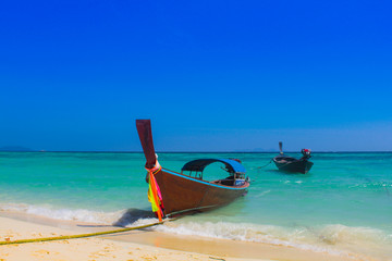 A fishing boat floats on Ko Lipe, Thailand on a day with clear blue sea and beautiful sunny skies.