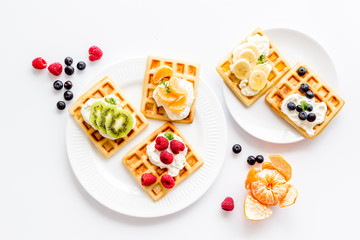 Fototapeta na wymiar Belgian waffles with creamy cheese and berries on white background top-down
