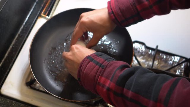 Cracking egg in the pan to fry an egg