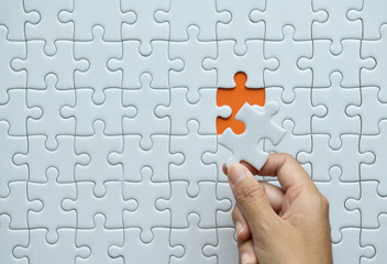Pieces of jigsaw puzzle in woman hands,Jigsaw puzzle white color on orange background