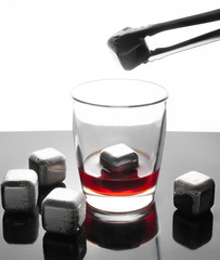 Steel cubes simulating ice for cooling drinks. Reusable. Silvery. On a dark mirror surface with...
