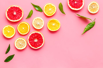 Citrus slices frame - lemons, grapefruits, leaves - on pink background top-down copy space