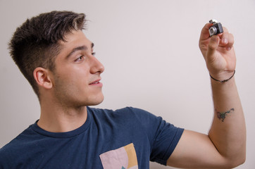 Young man taking a selfie with a mini camera