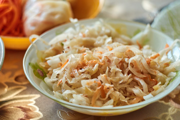 Sauerkraut in a ceramic plate on a textile background with a pattern