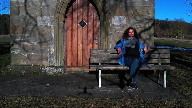 village girl sitting outside in front of a church slowmotion