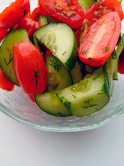 Vegetable salad of cucumbers and tomatoes with finely chopped dill in a glass bowl