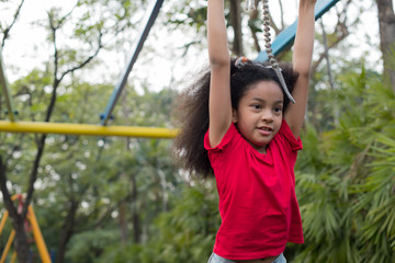 Fototapeta premium Afro american happiness little girl with curly hair in the playground in summer time with smile and laughing healthy, funny smiling face adorable lovely female kid. happy vacation lifestyle concept.