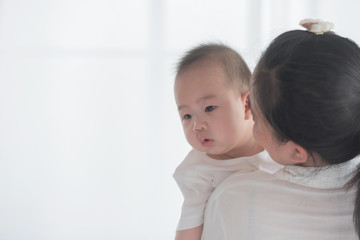 happy loving family. mother playing with her baby in the bedroom. asian mother hugging and holding her baby. family, motherhood, parenting, family and child care concept. White background.