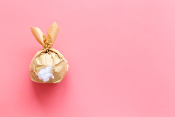 Easter gift in shape of bunny with tail on pink background top-down copy space