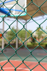 outdoor basketball court behind a metal fence vertical composition