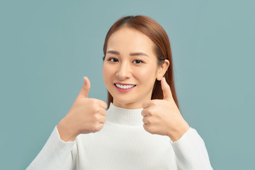 Smiling pretty young woman showing thumbs up isolated on the violet background