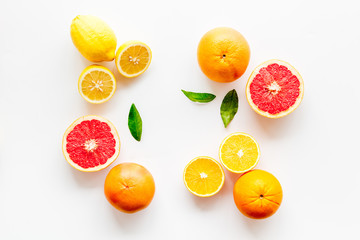 Fresh citrus background. Oranges, grapefruits, leaves - whole fruits and halfs - on white background top-down