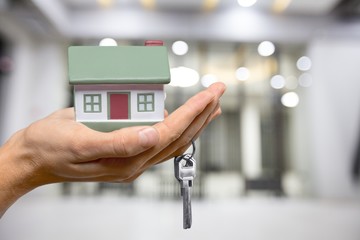 Human hand holding house model and keys