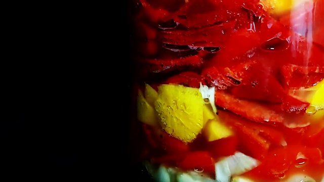 Chiles picantes y frutas fermentando en botella vidrio