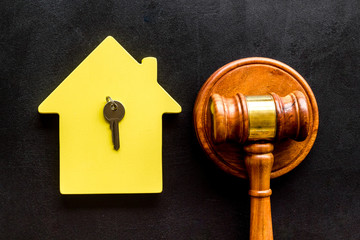 Mortgage court. Judge gavel near house on black background top-down