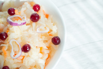 Sauerkraut with cranberries and onions in a white cup, closeup. The concept of proper nutrition and healthy eating. Selective focus, copy space for text.
