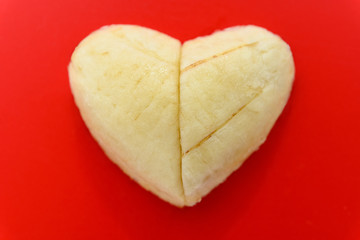two slices of banana shaped as a heart on red background
