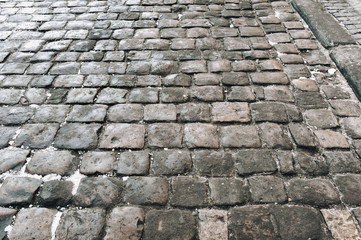 The gray paving stones close up. The texture of the old dark stone. Road surface. Vintage, grunge.
