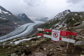 No trespassing sign near the Aletsch glacier near Bettmeralp in the Swiss alps on a cloudy day