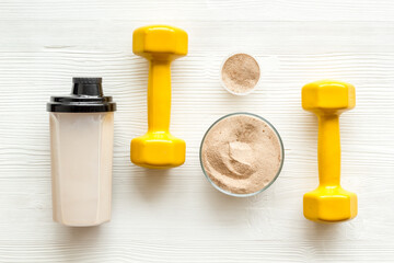 Sport nutrition. Whey protein, shaker, dumbbells on white background top-down flay lay