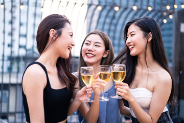 Group of young cute Asian girl gang best friends having party at rooftop restaurant. Girls drinking beer alcohol and toasting glass feeling happy enjoy, fun with smile face. Night lifestyle concept.