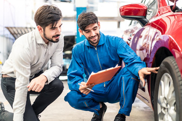 Vehicle maintenance handsome man servicer explain car condition to male customer in garage....