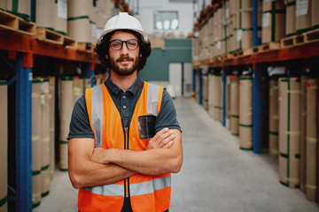 Portrait of confident worker wearing helmet and spectacles with orange vest uniform standing in...
