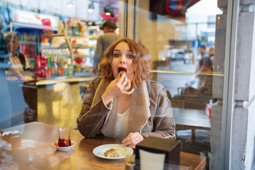 Redhead girl in the cafe eat sweets