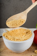 Dried garlic powder in a white stupa, wooden spoon with garlic powder, on a gray background.