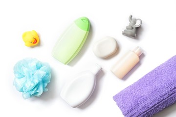 Flat lay photo baby care cosmetics, toiletries kit. Blue sponge, white shampoo bottle, green shower gel, body lotion, soap bar, rubber toys and purple cotton bath towel