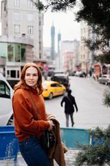 Fototapeta premium girl brown hair sits on a fence near the road 