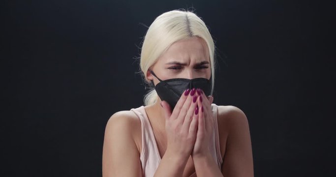 Young woman in black protective mask coughs and sneezes, Chinese coronavirus, epidemic of infection, protected from the virus, portrait of a woman.