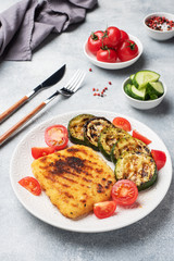 Schnitzel of chicken and zucchini cooked on the grill. Fresh tomatoes on a plate. Ready delicious dinner lunch.