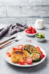 Schnitzel of chicken and zucchini cooked on the grill. Fresh tomatoes on a plate. Ready delicious...