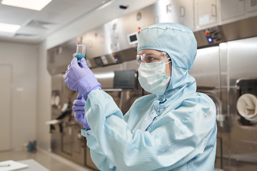 Scientists in protective suits in a medical laboratory conduct medical research in search of a...