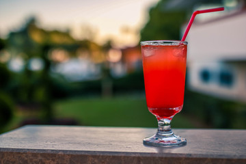 Alcoholic red cocktail with a straw on the background of the hotel.