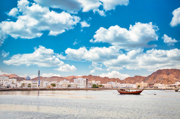 Muscat Coastline alongwith the mountains and blue sky. A traditional Dhow anchored at the port....
