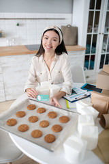 Joyful young girl showing her pastries and a business card.