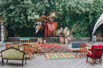 the wedding ceremony area is decorated with tropical-style decorations, colored flowers, wicker vases, carpets, in the garden on the terrace