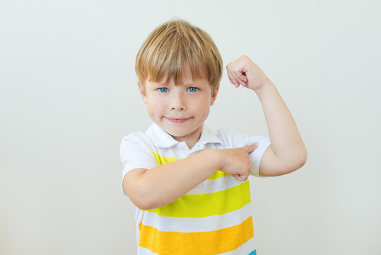 Portrait of a strong kid showing the muscles of his arms on white background
