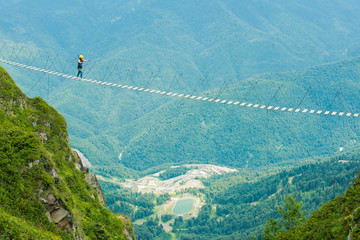 Young woman crossing the chasm on the rope bridge