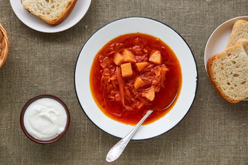 Vegetable beet soup in a white bowl on a textile background