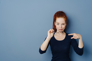 Cute fun young woman pointing to her glasses