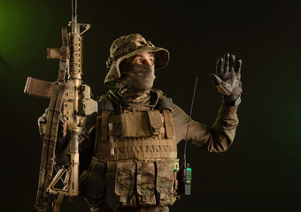 a saboteur soldier in military clothing with a weapon on a dark background surrenders with his hands up - Powered by Adobe