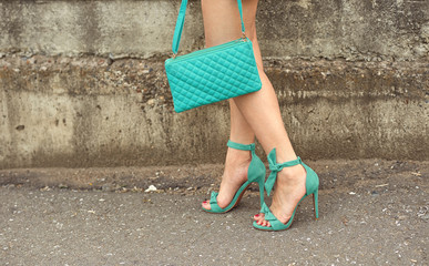 Step girls in sandals in high heels with a bag in her hand.