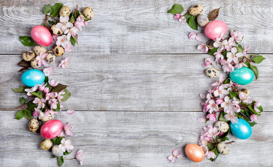 Easter layout of pink Apple tree flowers, quail and colored Easter eggs as arcs with copy space.