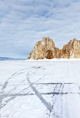 Fototapeta na wymiar Baikal Lake in the winter. Snow-covered frozen Small Sea Strait. View of the famous Shamanka Rock - a natural landmark of Olkhon Islands on a frosty February day