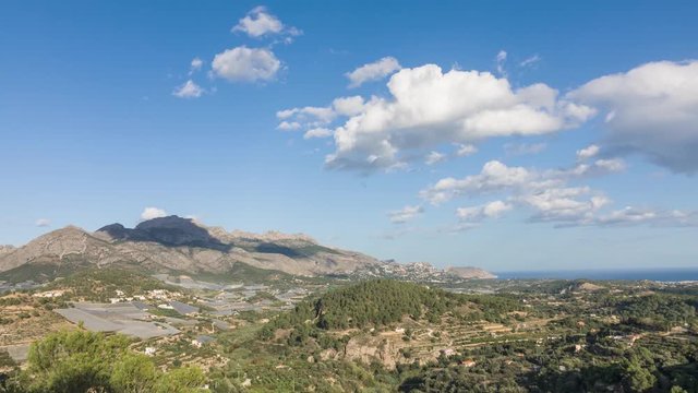 Clouds appear over mountainous terrain with the mediterranean sea in the background. Zoom out.